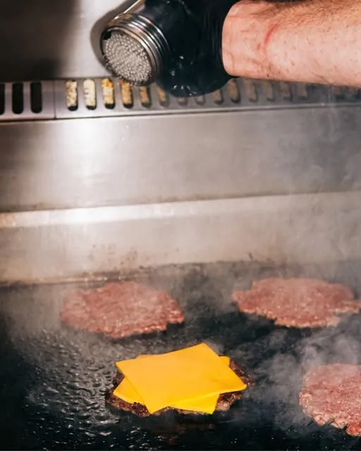 Seasoning smash patties on the grill